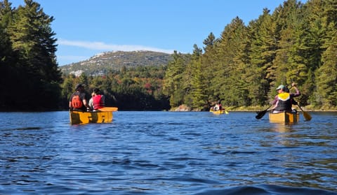 Canoes on a lake below high rounded hills in fall colour