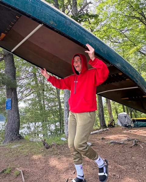 A woman carries a canoe above her head